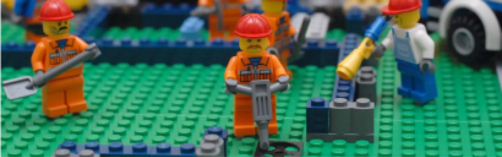Lego minifigures wearing hard hats doing construction work.